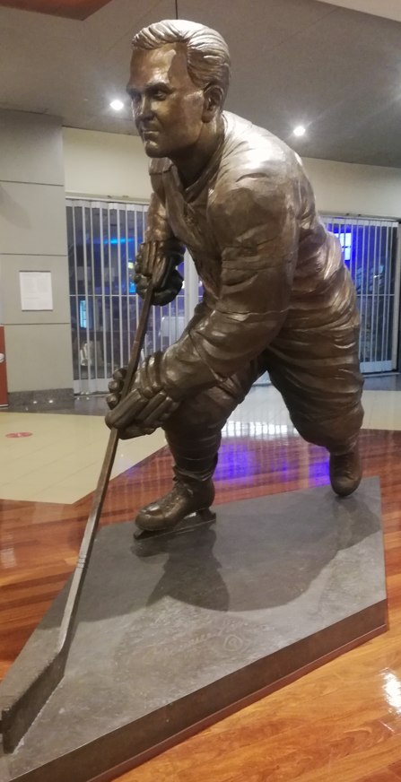 Una estatua en bronce de Maurice Richard, patinando hacia delante y con el palo de hockey.