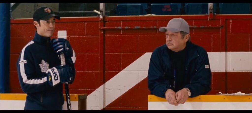 Eric con una sudadera de los Leafs, haciendo de assistant coach del equipo infantil de Scot.